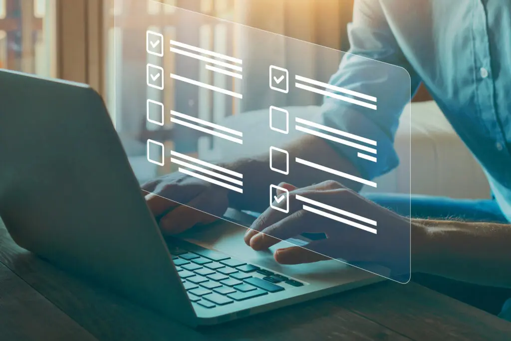 Person typing on laptop with digital checklist overlays.