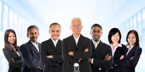 A diverse group of four confident businessmen in suits standing with arms crossed.