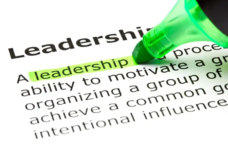 Highlighting the word 'Leadership' with a green marker on a printed page.