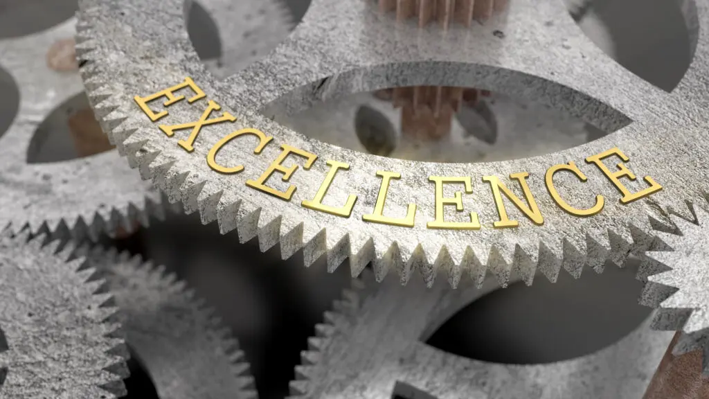 Close-up of golden 'EXCELLENCE' on metallic gears.