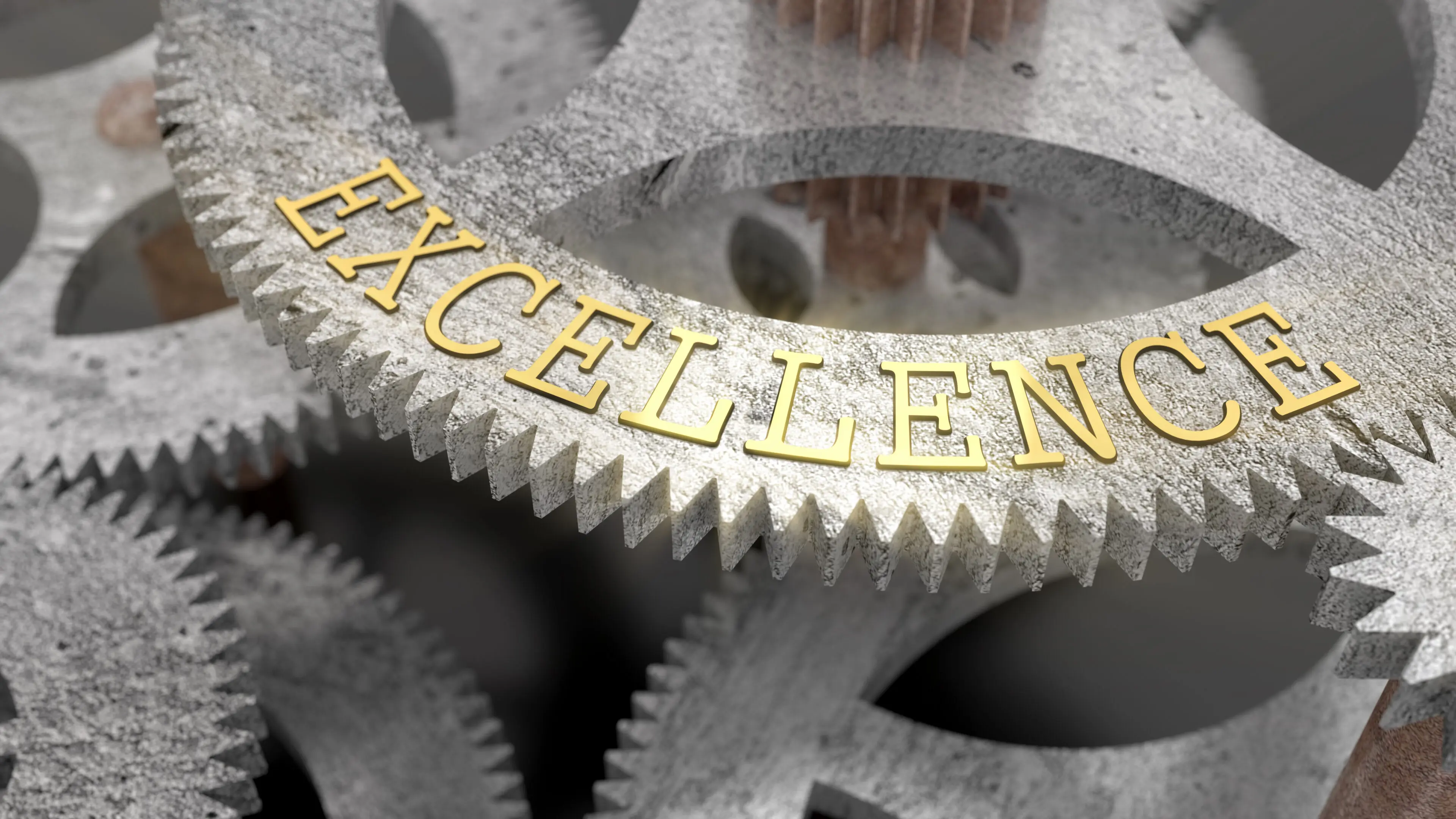 Close-up of golden 'EXCELLENCE' on metallic gears.