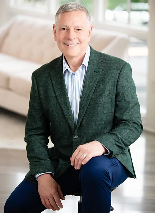 Smiling man sitting in bright room.