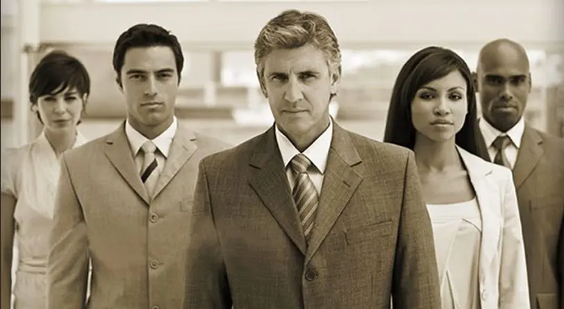 Three serious professionals in business attire posing indoors.