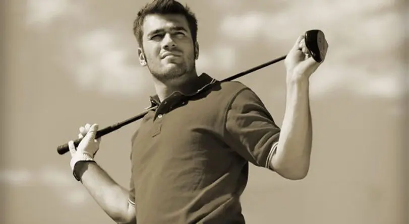 Confident man holding a golf club over his shoulder outdoors.